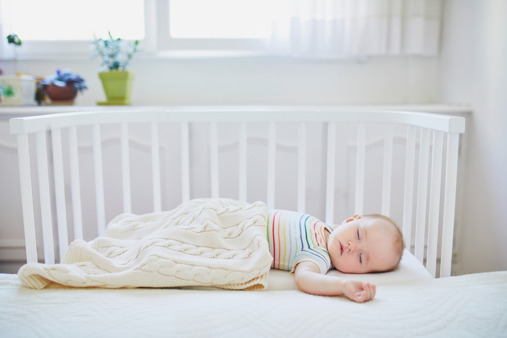 Adorable baby sleeping on crib mattress